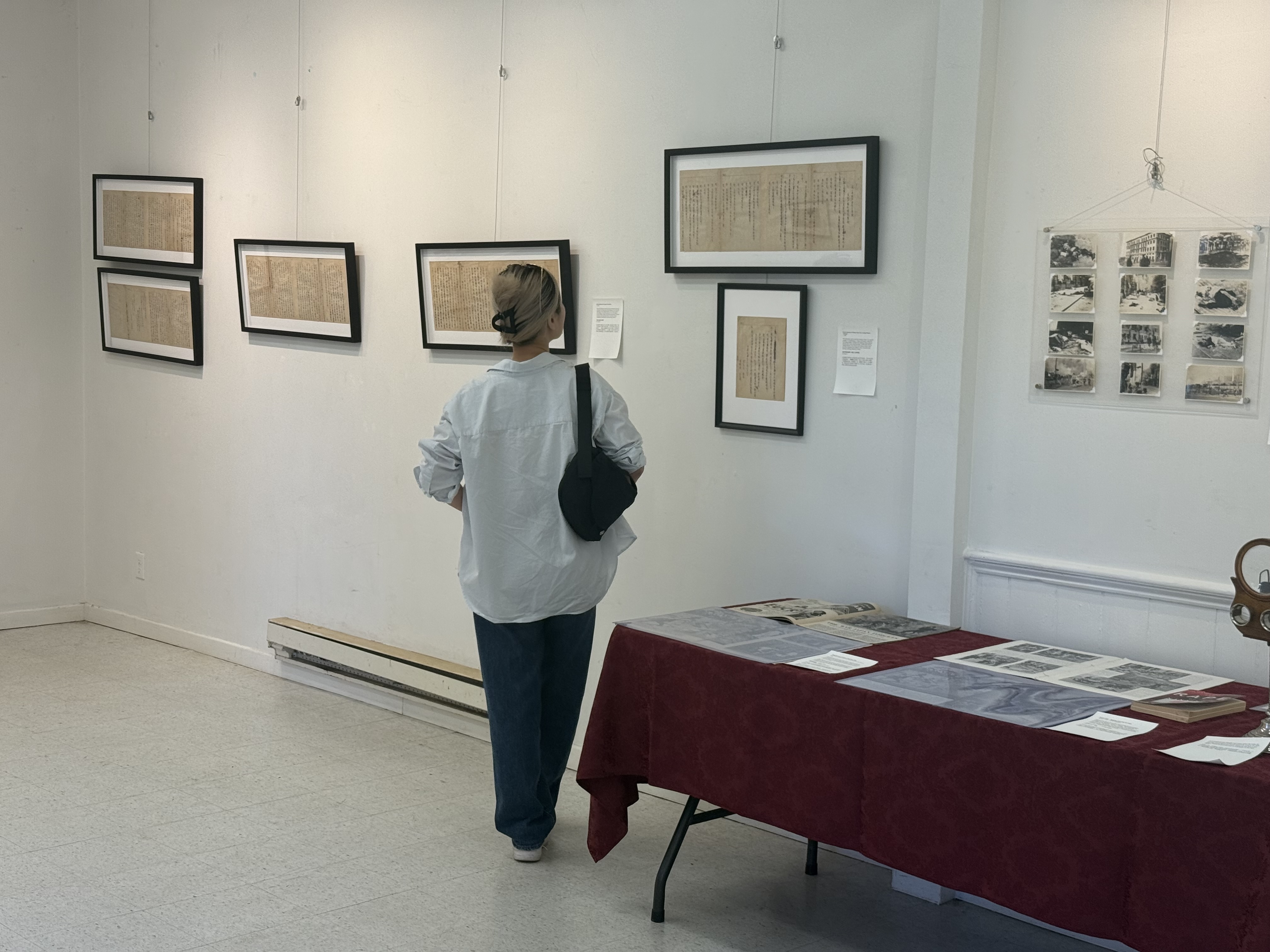 Visitor viewing framed archival documents and wartime photographs.
