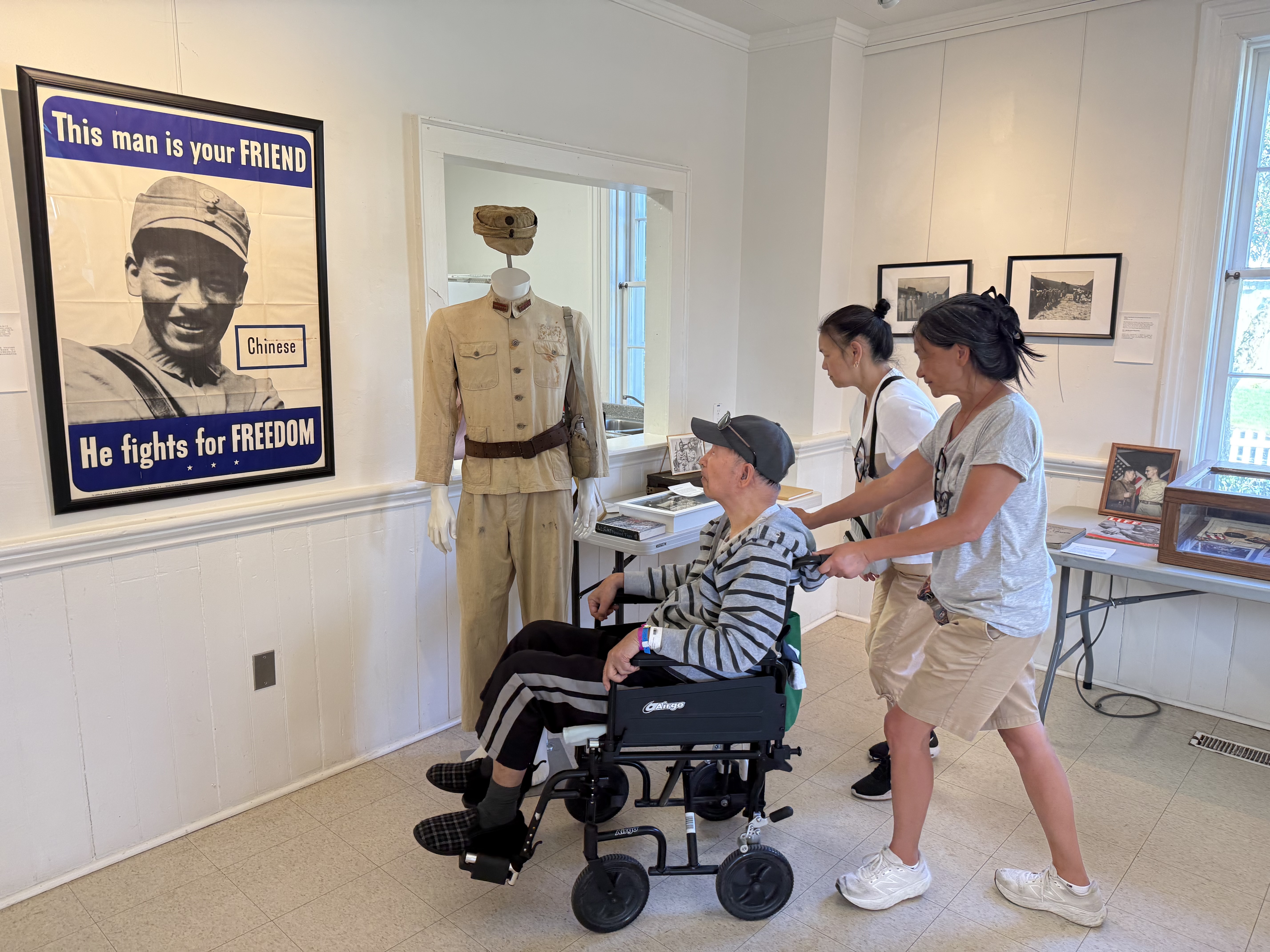 Visitors standing near a Chinese wartime uniform and Allied poster display.